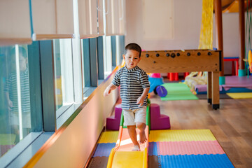 Cute asian little boy is playing on the indoor playground or playroom.