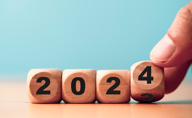 Wall Mural - hand flipping of 2023 to 2024 on wooden block cube for preparation new year change and start new bus