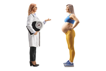 Wall Mural - Full length profile shot of a female doctor holding a weight scale and talking to a pregnant woman in sportswear