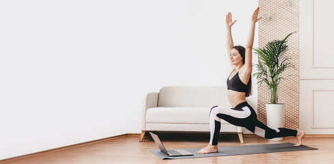 Young woman does yoga exercises with a laptop at home web banner