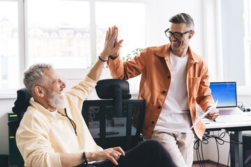 Cheerful colleagues giving high five in modern office space