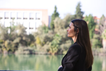 Beautiful young woman leaning over the railing of the river in Seville, Spain. The photo is taken from behind and she is looking at the horizon where you can see the other bank.