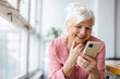 © pikselstock - Smiling senior woman using smartphone