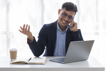 Wall Mural - Cheerful business Asian man freelancer making telephone call share good news about project working in office workplace, Asian business man planning finance concept.