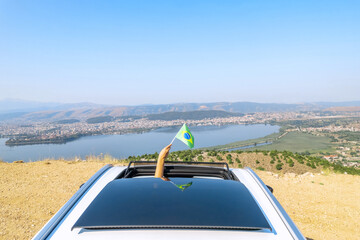 Wall Mural - Woman holding Brazil flag from the open car sunroof,  window driving along the serpentine road in the mountains. Top view. Concept