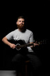 © Volodymyr - Handsome brunette bearded man musician plays an acoustic guitar in a black room. Ready to play a music.