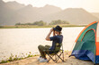 Man camping tourist with binoculars sitting on sand beach near touristic tent