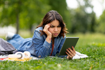 Stressed young arab woman looking at digital tablet screen outdoors and frowning