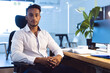 © Wavebreak Media - Portrait of biracial businessman sitting at desk and looking at camera, working late at office