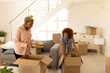 © Wavebreak Media - Diverse young woman looking at shocked girlfriend holding books while unpacking boxes in new home