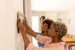 © Wavebreak Media - Smiling multiracial young lesbian couple hanging picture frame on wall in new home