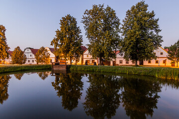 Canvas Print - Pond and traditional houses of rural baroque style in Holasovice village, Czech Republic