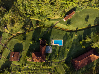 Aerial view of beautiful forest full of nature and pasture fields in Tremembé in Vale da Paraíba in São Paulo. Mountains and hills in sunny day. Lots of green and tropical vegetation. Drone. Sunset