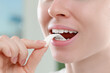 © New Africa - Woman putting chewing gum piece into mouth on blurred background, closeup