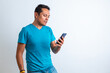 © Hector - Hombre seriode piel morena de playera azul revisando el celular con fondo blanco