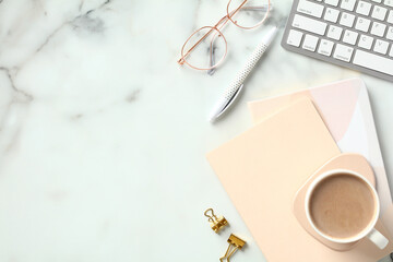 Fototapete - Elegant feminine workspace with paper notebooks, cup of coffee, keyboard, glasses on marble background. Stylish home office desk table. Top view. Flat lay.