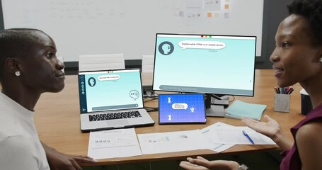 Diverse businesswomen in office using computers with ai digital messaging on screens