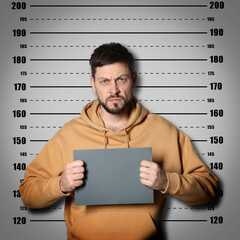 Criminal mugshot. Arrested man with blank card against height chart