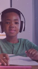 Canvas Print - Animation of lights over happy african american boy wearing headphones and doing homework