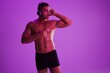 © SHOTPRIME STUDIO - Man wearing headphones athletic physique bodybuilder nude torso abs full-length, fitness classes, purple colored light. Advertising, sports, active lifestyle, competition, challenge concept.