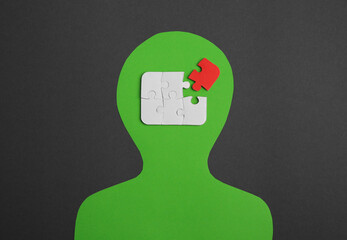 Poster - Human paper cutout with jigsaw puzzles in head, red piece as solution idea on black background, flat lay