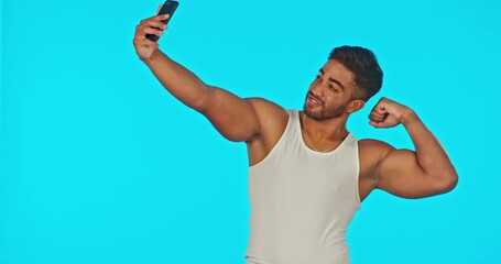 Poster - Selfie, smile and bicep muscle of man in studio isolated on a blue background for fitness. Photographer, flexing emoji and happy male model taking photo for profile picture, social media and workout.