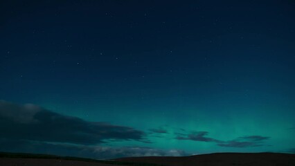 Wall Mural - Time lapse of the aurora borealis (the northern lights) on a moonlit night with clouds passing by. Filmed in the village of Back on the Isle of Lewis, part of the Outer Hebrides of Scotland.