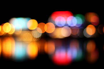 Blurred evening night city lights view reflected in water. Abstract bokeh background. Colorful bokeh.
