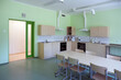 © Mint Images - A modern school, a kitchen with fitted cupboards and ovens, a long table and chairs.