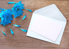 White Card Paper For Writing Messages Is Placed On A Light Green Envelope Decorated With Bright Blue Flowers. Christmas, New Year, Winter Holidays And Birthday Concept. Greeting Card..