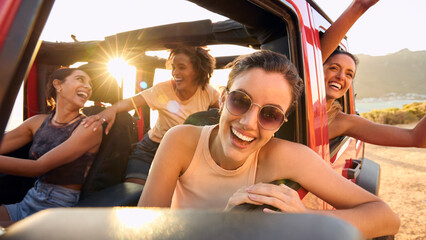 Wall Mural - Portrait Of Laughing Female Friends Having Fun In Open Top Car On Road Trip