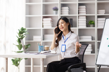 Wall Mural - Cheerful business Asian woman freelancer making telephone call share good news about project working in office workplace, employee business finance concept.