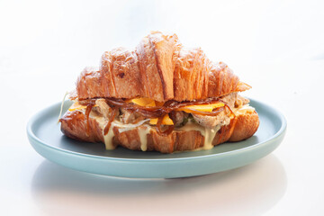 Wall Mural - Brioche croissant chicken sandwich on a pink plate white background.