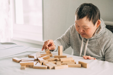 elderly woman with down syndrome and an Asian girl play in tower from wooden blocks