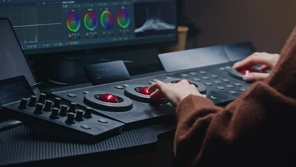Fototapete - Female editor works in studio, uses digital color grading control panel. Colorist makes video color correction on computer. Program interface with RGB graphics, color wheels and levels on PC monitor.