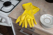 Kitchen composition of rubber yellow gloves and a set of plates on the nightstand, in the kitchen. An image about housework, apartment care and cleanliness.
