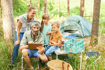 Wall Mural - Man sharing digital tablet with family at campsite