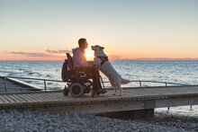 Man With Disability With His Service Dog At Sunset Using Electric Wheelchair.