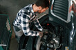 © standret - Using the tool and fixing the car. Man in uniform is working in the auto salon
