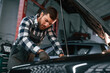 © standret - Focused on work. Repairing the car. Man in uniform is in the auto salon