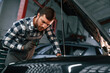 © standret - Focused on work. Repairing the car. Man in uniform is in the auto salon