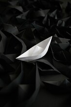 Unique White Paper Origami Ship Among Black Ones