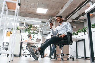 Handsome indian man is sitting on the chair and working in the office