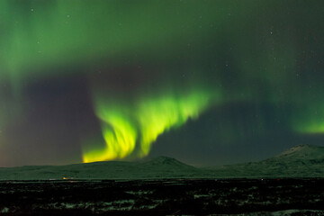 imagen de un paisaje nocturno nevado, con montañas de fondo, y una aurora boreal sobre el cielo de i