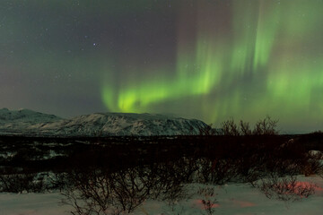 imagen nocturna de un paisaje nevado con una aurora boreal en el cielo nocturno de islandia