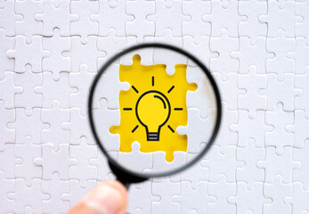 Creative Thinking idea and Innovation concept.,Hand holding magnifying glass focus on missing white jigsaw and puzzle with light bulb icon.