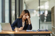 © ArLawKa - Stressed and frustrated asian female accountant sitting at desk making serious business decisions Worried about the project she's working on and the pain in her eyes looking at the screen?