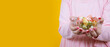Sugar feast banner, caucasian girl holding colorful hard candies for sugar feast banner. Yellow studio background, copy space. Greeting, celebrating religious concept design. Many treats.