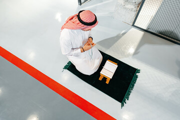 Young arab muslim man reading the holy Quran in the office