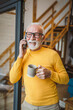 © Miljan Živković - One senior man stand in at door of tiny house in day use smart phone